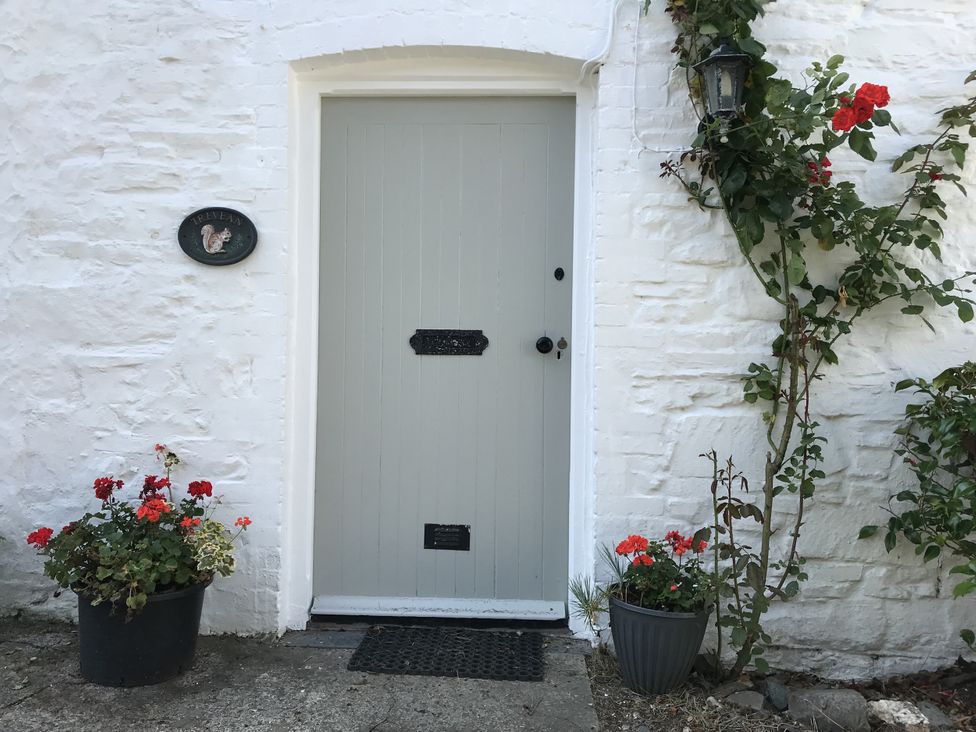 A grey door with flowers and a nameplate at Trevean in Crackington Haven