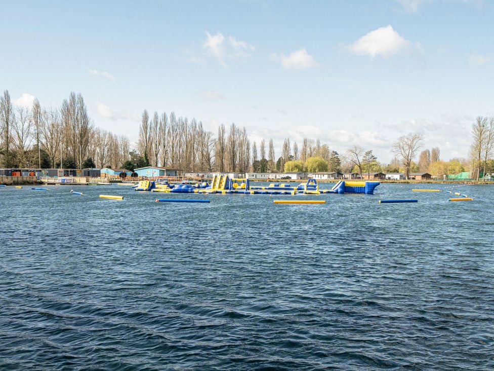 A lake with inflatable obstacles and cabins at Skylight Stargazer - Billing Aquadrome