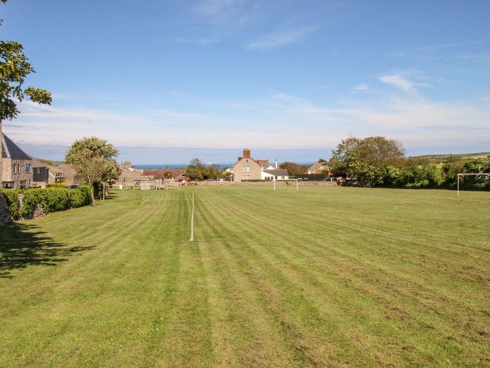 A grassy field with goalposts and homes in the background at Mallow Cottage in Langton Matravers