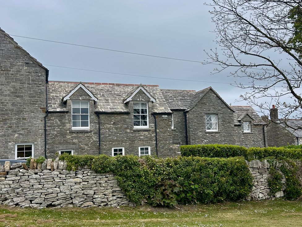 A stone house with windows and slate roof at Mallow Cottage in Langton Matravers