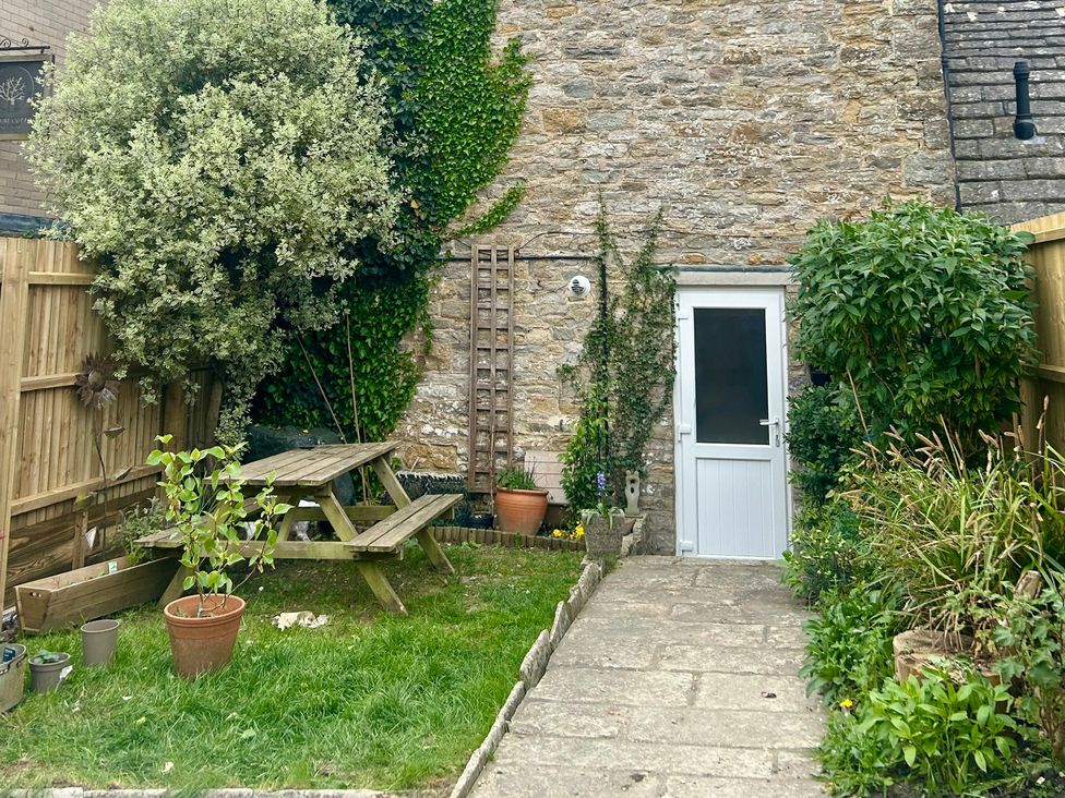 A garden with a picnic table and plants at Mallow Cottage in Langton Matravers