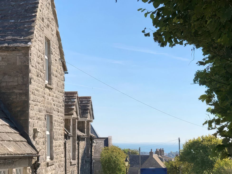An outdoor view of stone buildings under a clear sky at Mallow Cottage in Langton Matravers