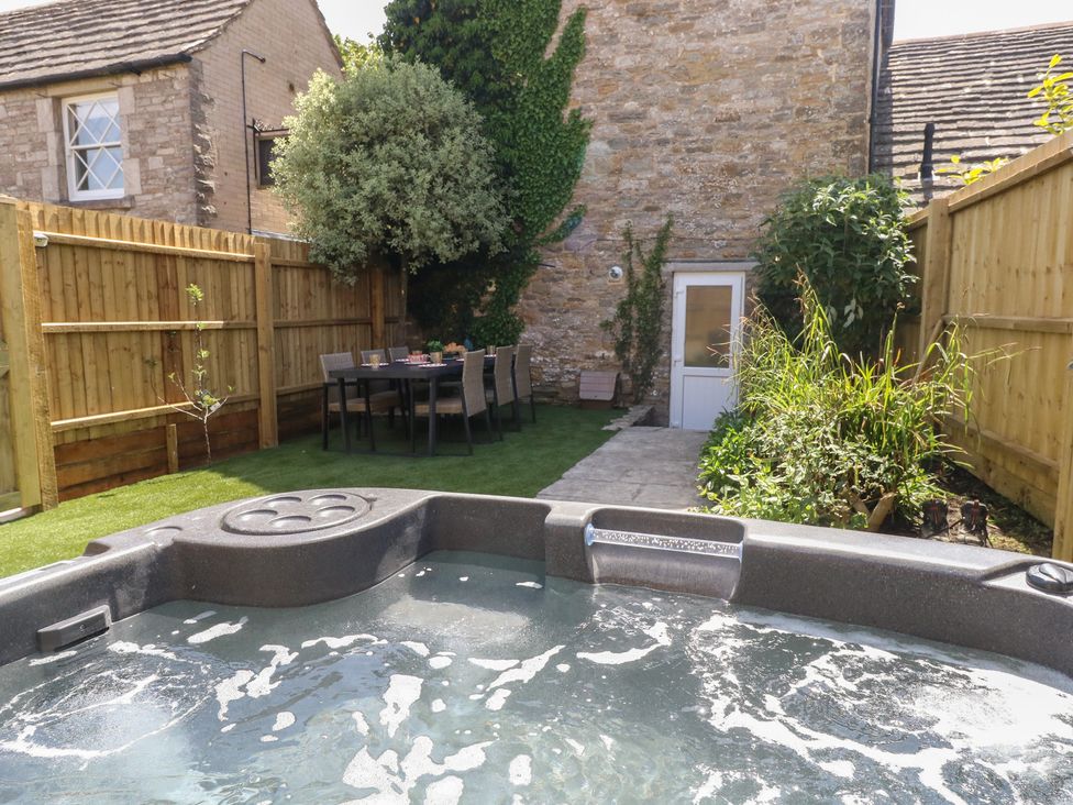 A garden with a hot tub and dining table at Mallow Cottage in Langton Matravers