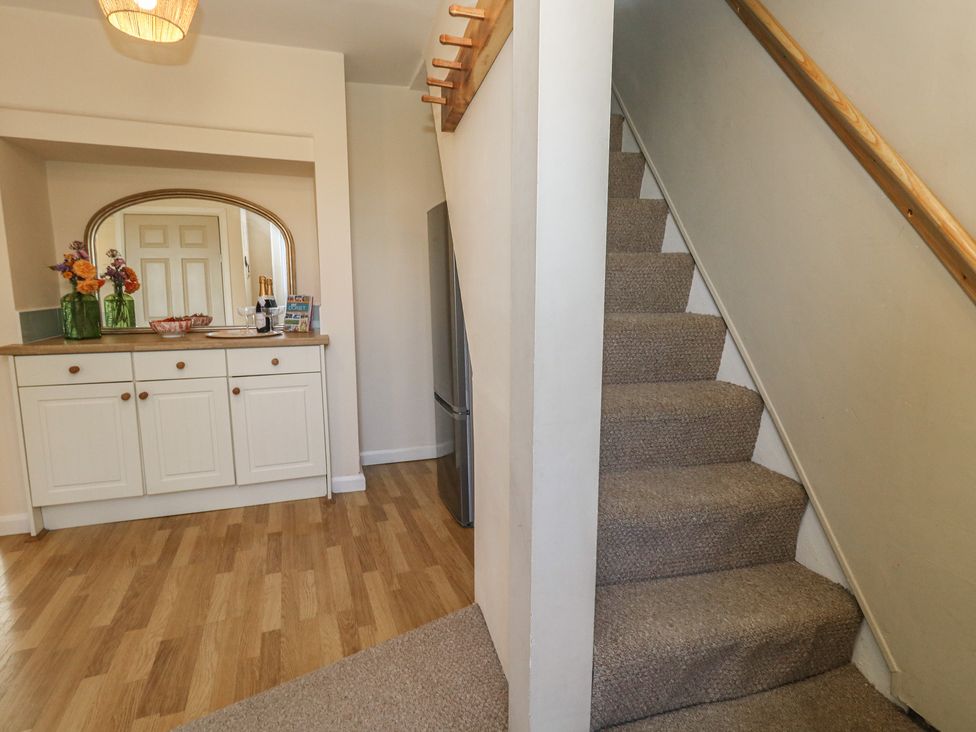 A hallway with a staircase and sideboard at Mallow Cottage in Langton Matravers
