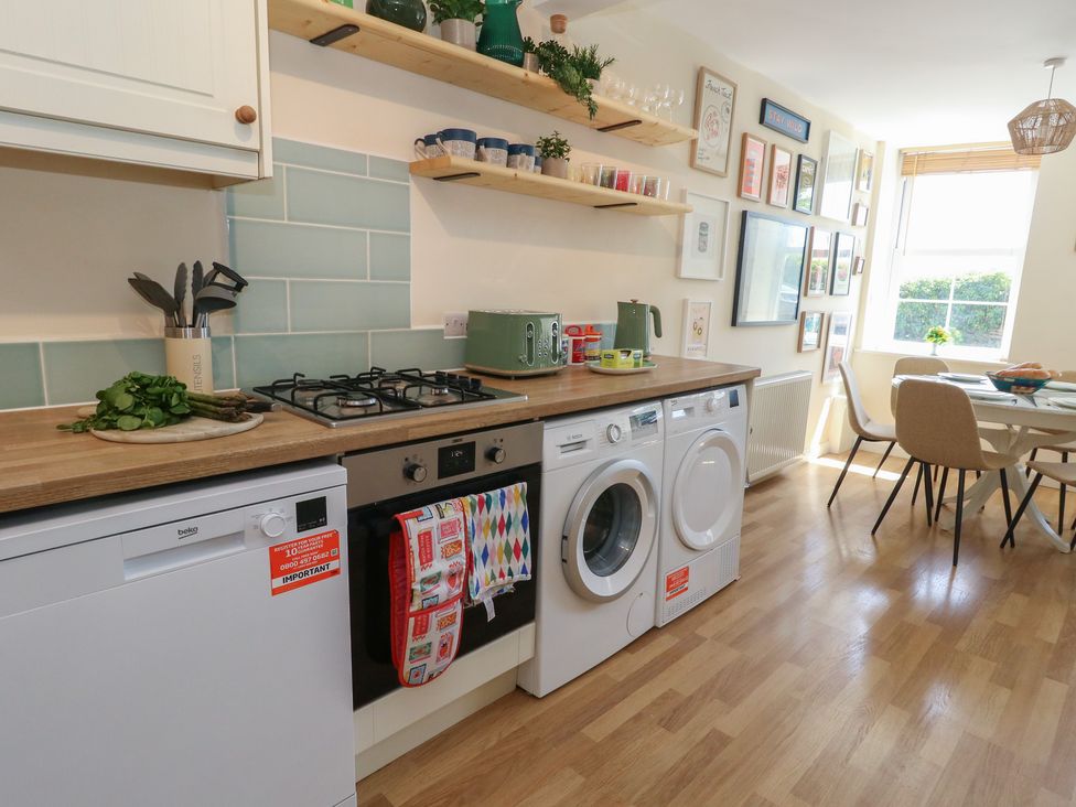 A kitchen with appliances and dining area at Mallow Cottage in Langton Matravers