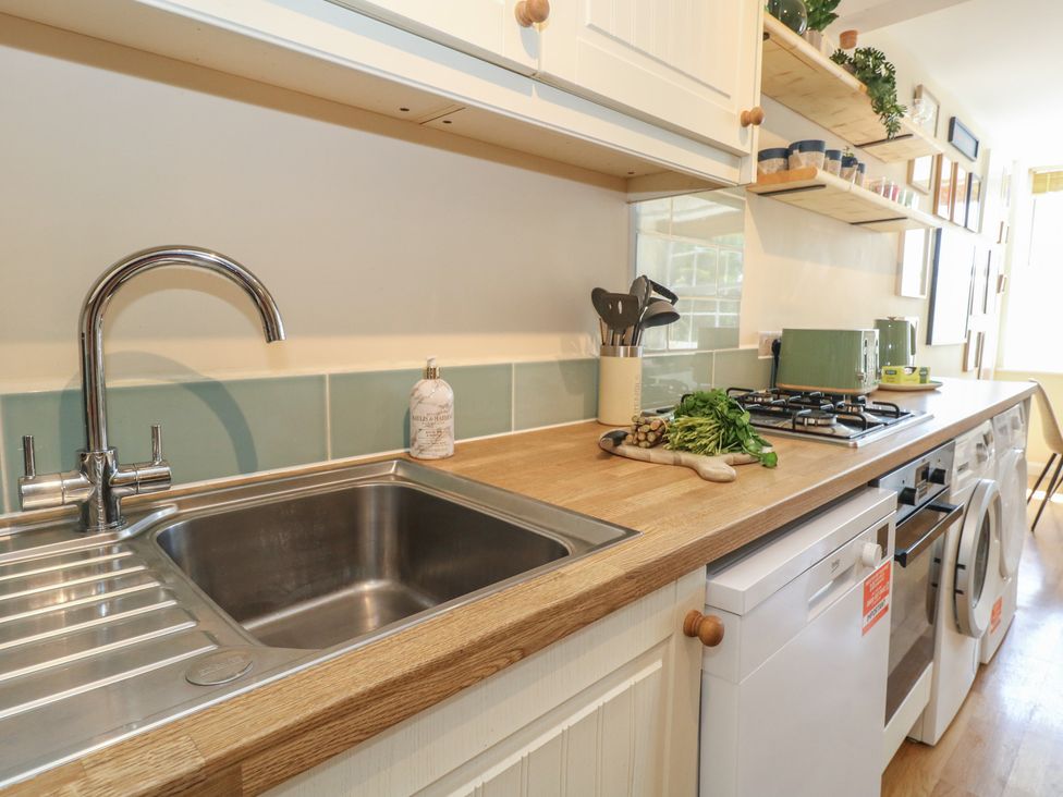A kitchen with a sink and gas stove at Mallow Cottage in Langton Matravers