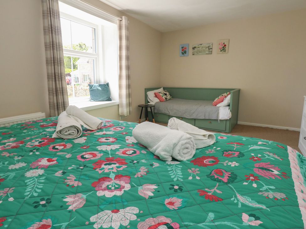 A bedroom with a bed and a sofa at Mallow Cottage in Langton Matravers