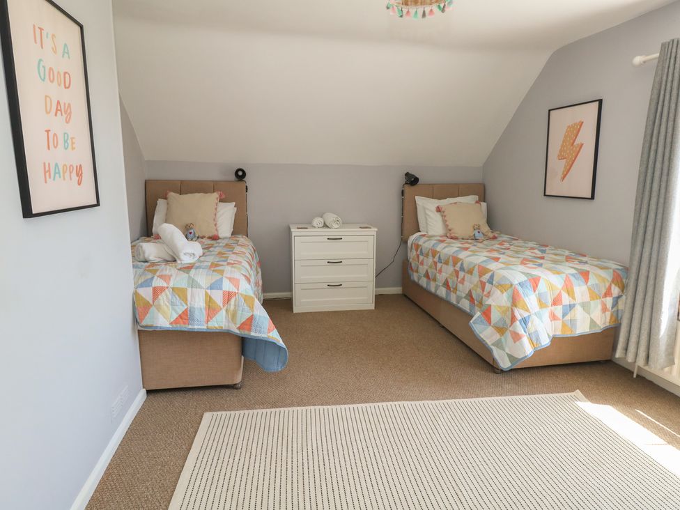 A bedroom with two beds and a dresser at Mallow Cottage in Langton Matravers