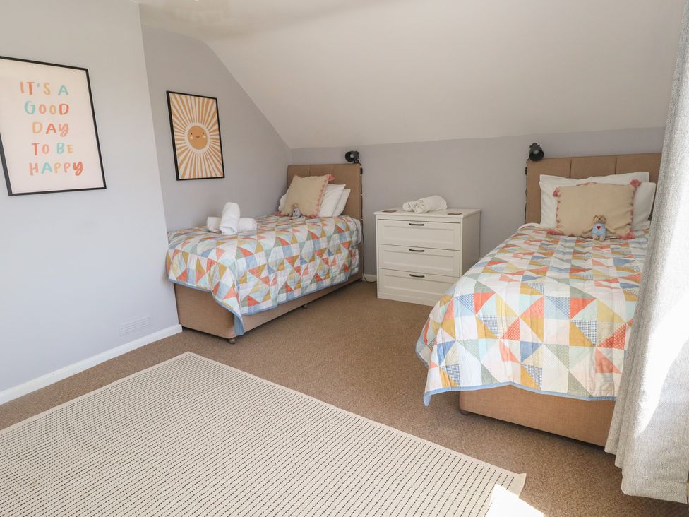 A bedroom with two beds and a dresser at Mallow Cottage in Langton Matravers