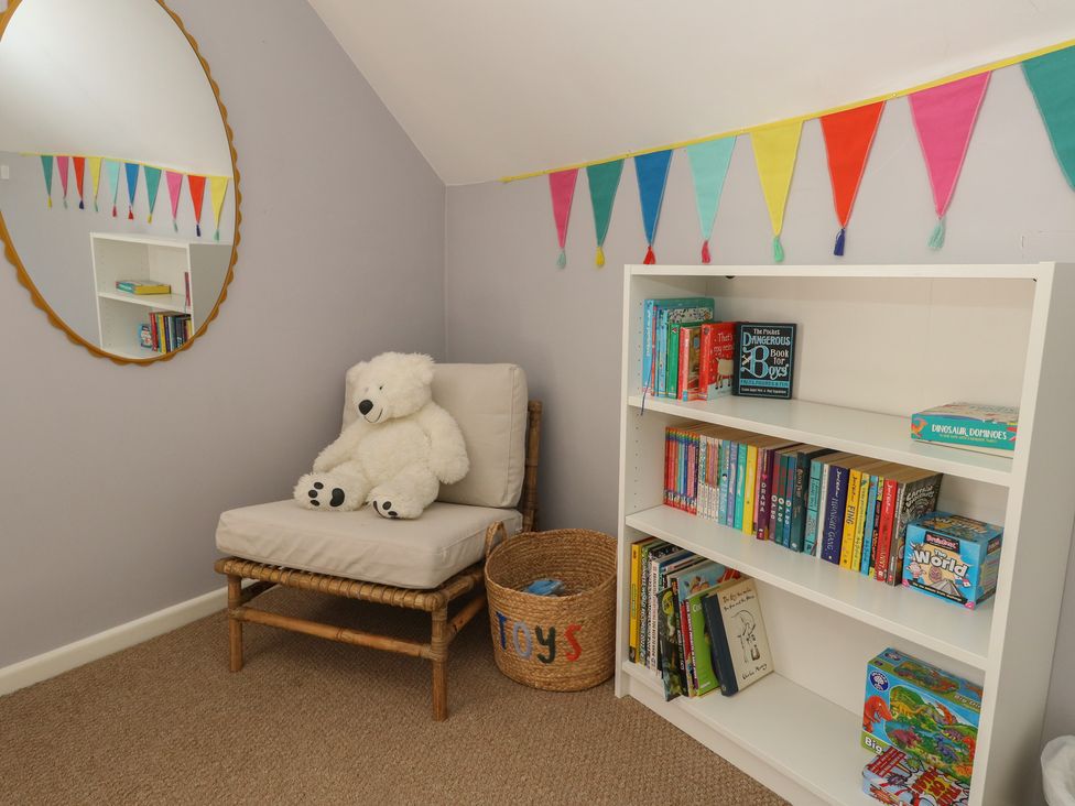 A reading room with a chair and bookshelves at Mallow Cottage in Langton Matravers