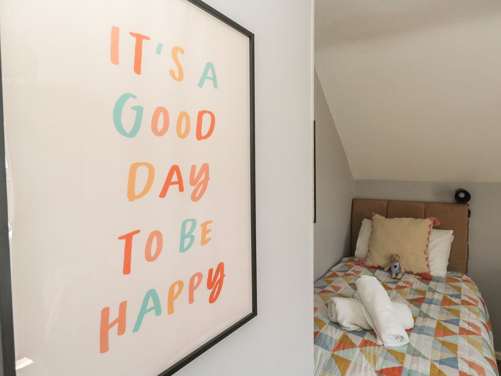A bedroom with a bed and a framed picture at Mallow Cottage in Langton Matravers