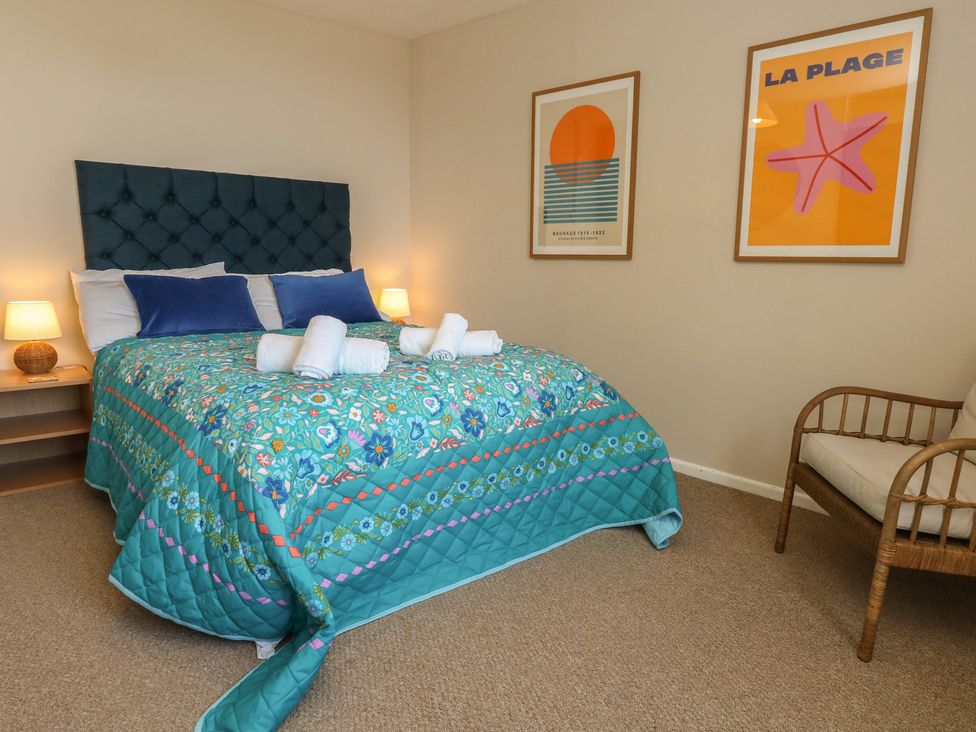 A bedroom with a bed and wall art at Mallow Cottage in Langton Matravers
