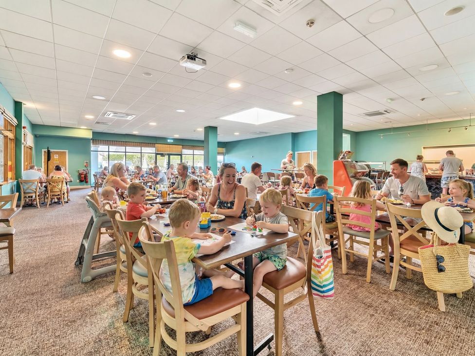 A dining room with families enjoying meals at Dune Delight - Hayling Island