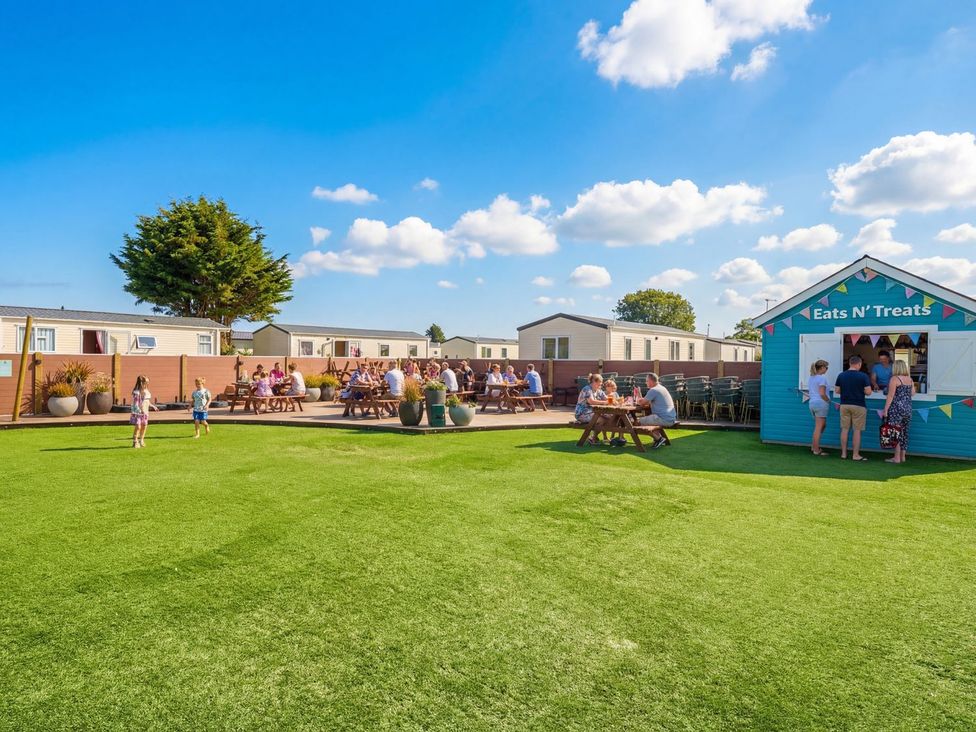 An outdoor area with a food kiosk and picnic tables at Dune Delight - Hayling Island