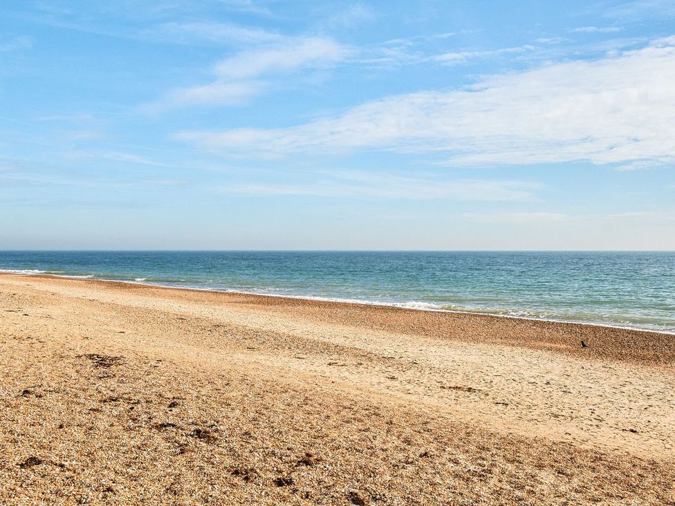 A beach with sand and ocean waves at Dune Delight - Hayling Island