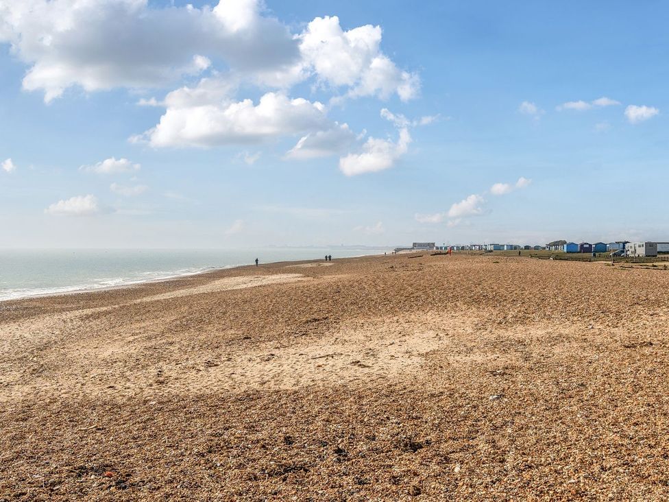 A beach with pebbles and beach huts in the distance at Dune Delight - Hayling Island Hayling Island Holiday Park