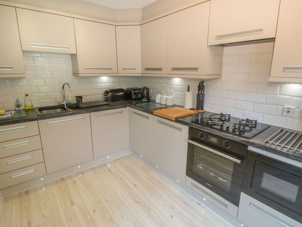 A kitchen with cabinets, a sink, a stove, and appliances at The Shipwrights in Whitby