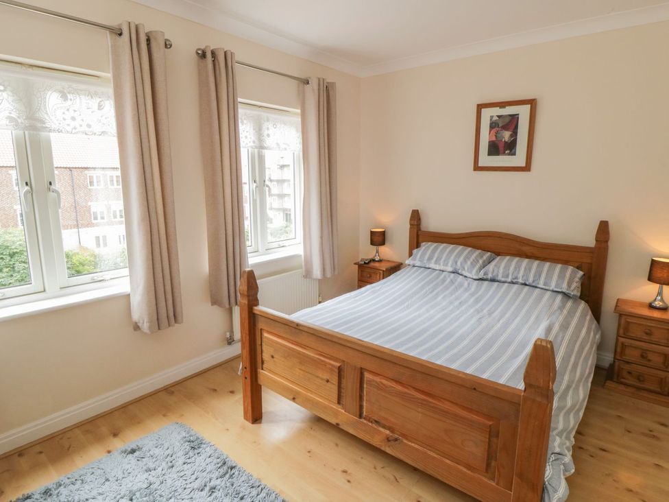 A bedroom with a wooden bed and windows at The Shipwrights in Whitby