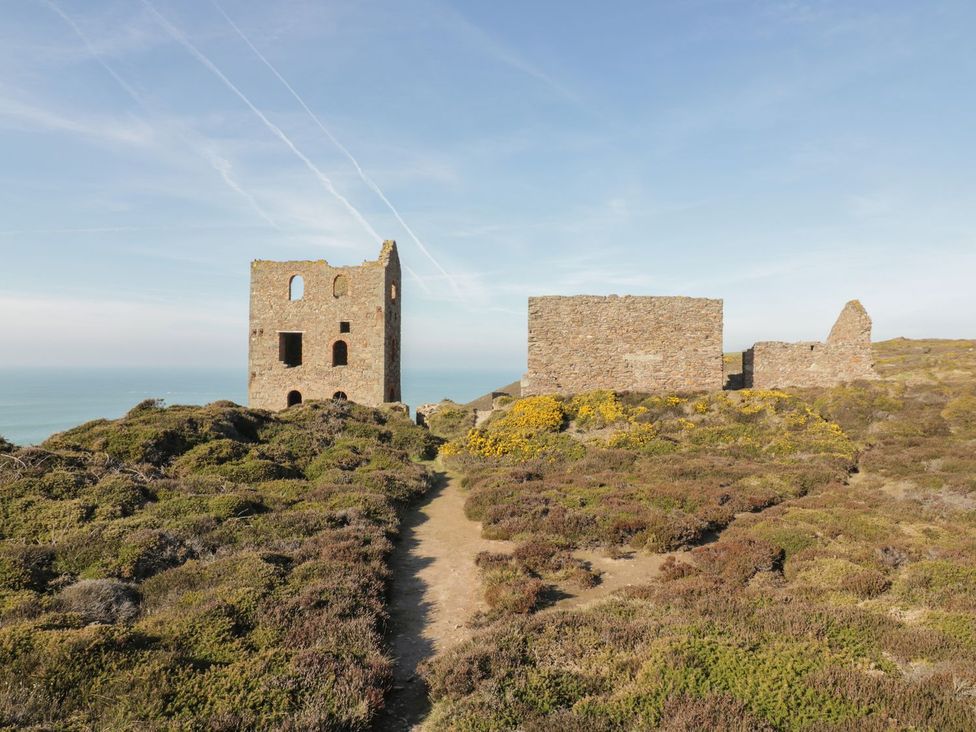 Ruins on a hillside with vegetation and a pathway at Chy Vean in St. Agnes