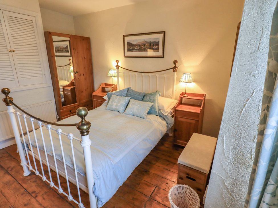 A bedroom with a bed and wardrobe at Stoker’s Cottage in Windermere