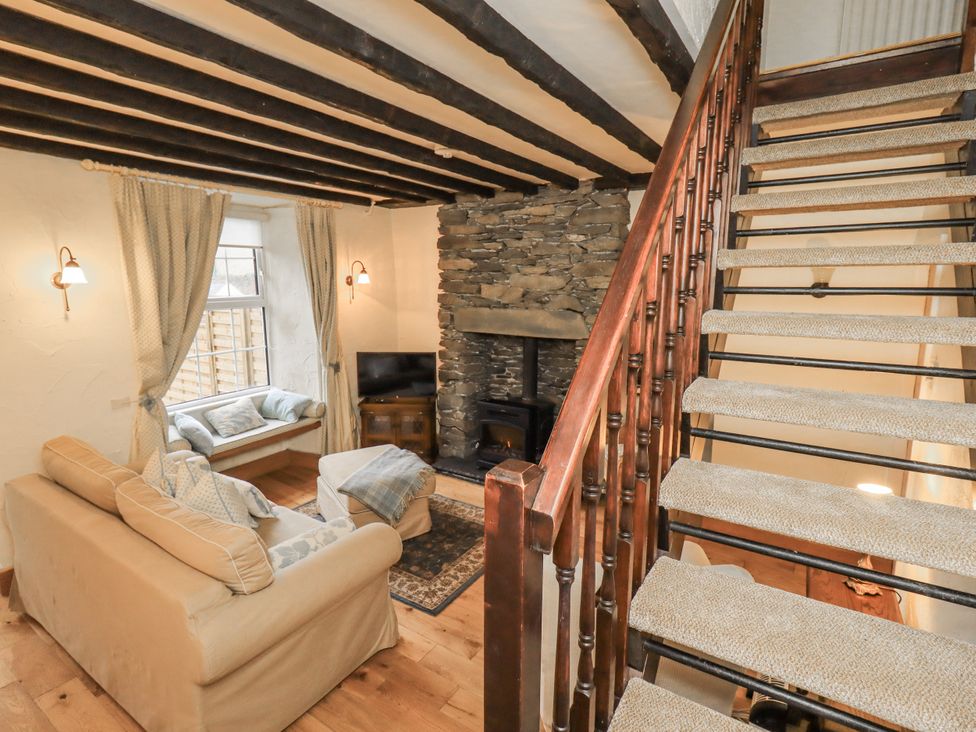 A living room with a sofa and a stone fireplace at Stoker's Cottage Bowness-On-Windermere