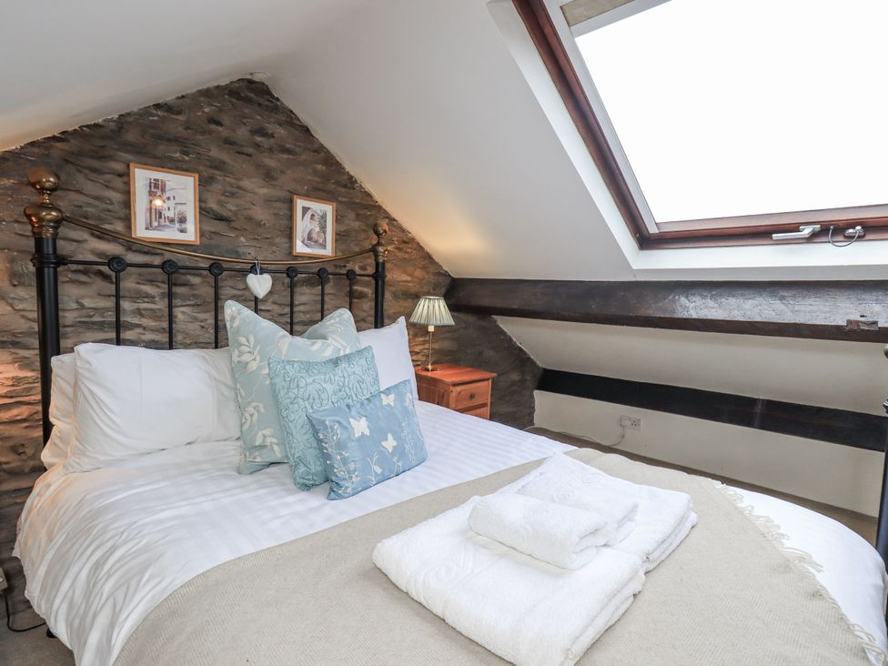A bedroom with a bed and decorative pillows at Stoker’s Cottage, Bowness-On-Windermere