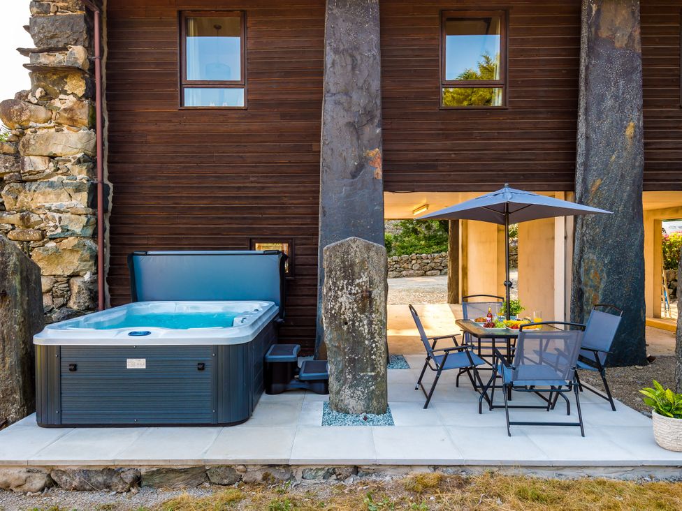 An outdoor area with a hot tub and dining table at Idris Barn Dolgellau