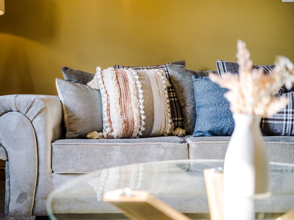 A couch with pillows and a vase with a plant at Idris Barn Dolgellau