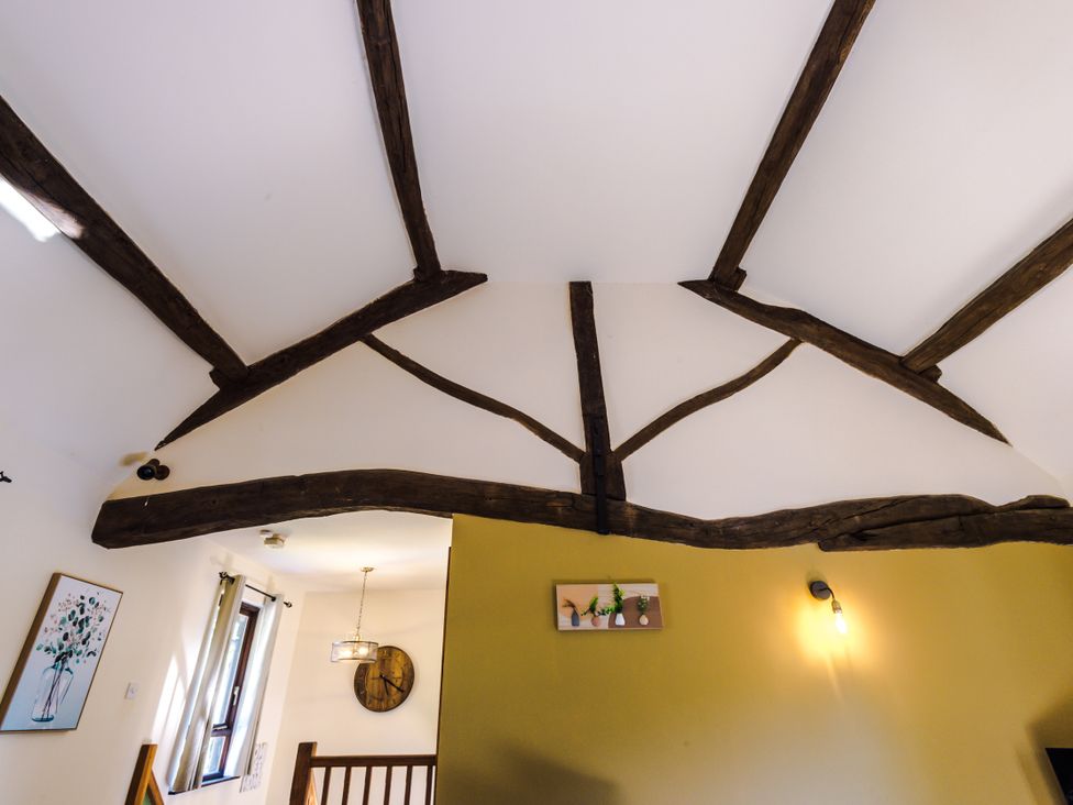 A ceiling with wooden beams and wall decor at Idris Barn Dolgellau