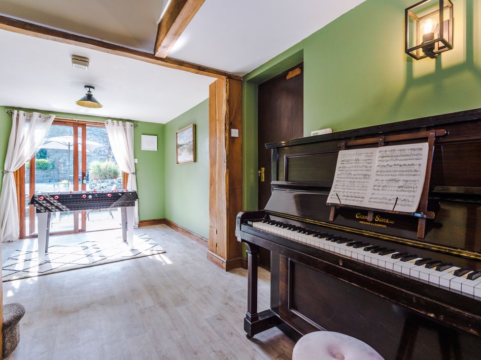 A snug room with a piano and foosball table at Idris Barn in Dolgellau