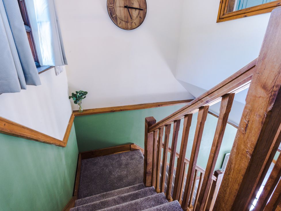 A staircase with wooden railing and a clock at Idris Barn in Dolgellau