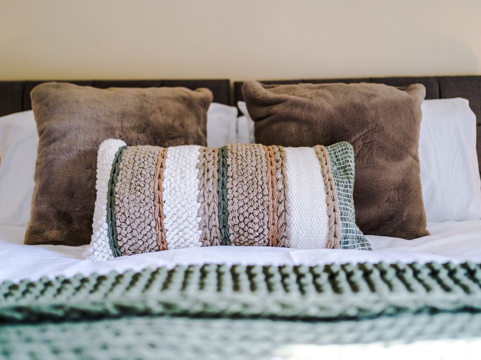 A bed with pillows and a decorative pillow at Idris Barn Dolgellau