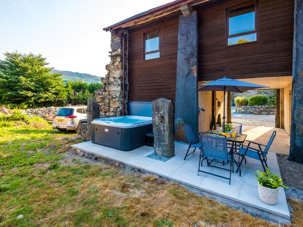 An outdoor area with a hot tub and seating at Idris Barn Dolgellau
