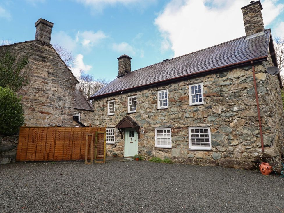 A stone house with a fence in an outdoor area at Cader Cottage Dolgellau