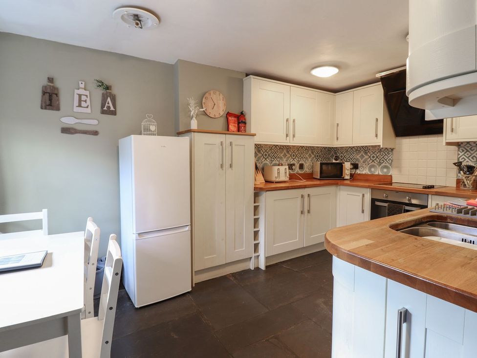 A kitchen with cabinets and a table at Cader Cottage in Dolgellau