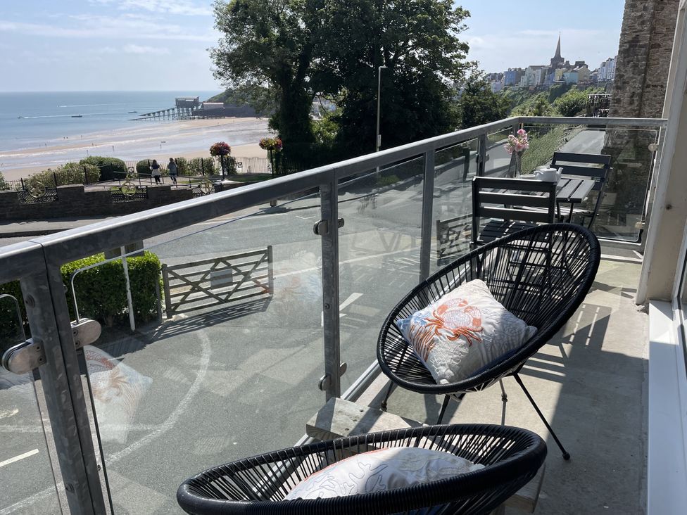 A balcony with chairs and a table overlooking the ocean at 10 Croft Court in Tenby