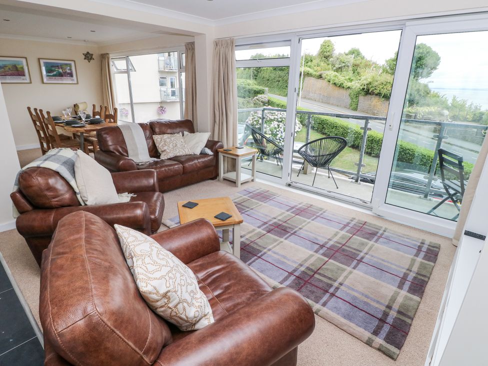 A living room with leather sofas and a view of the balcony at Lifeboat Lookout in Tenby