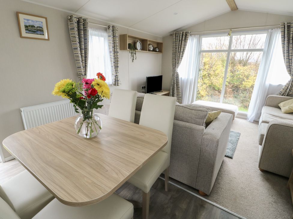 A living room with a dining table and flowers in a vase at No.22