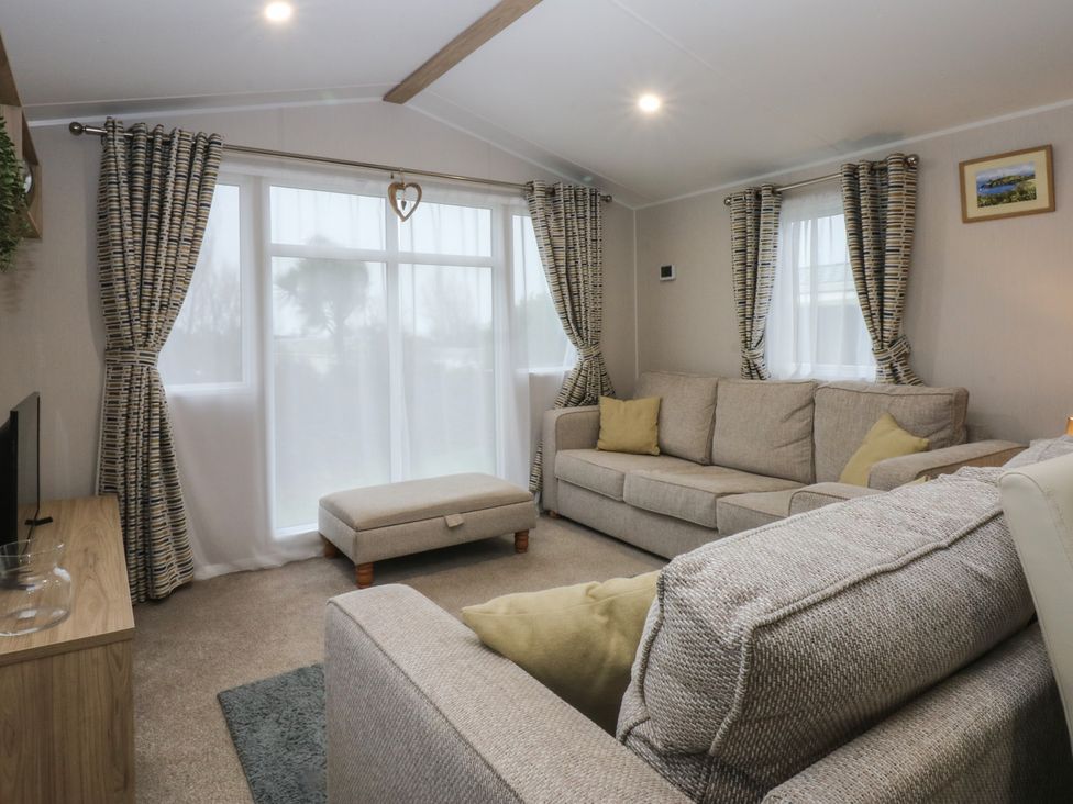 A living room with a sofa and an ottoman at Woodland Way in Benllech