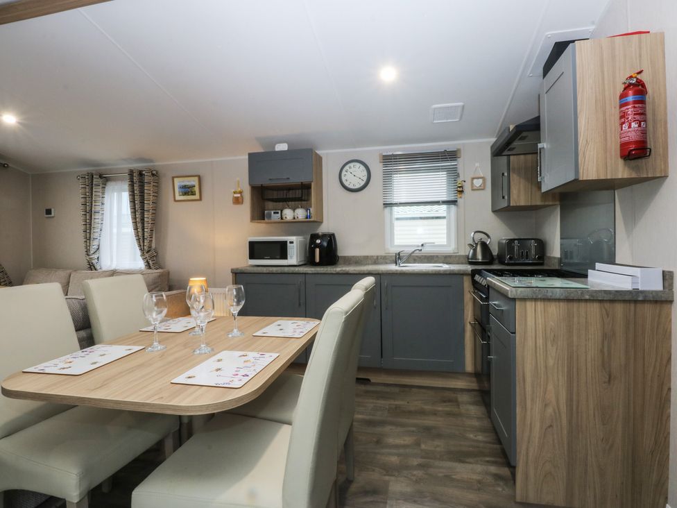 A kitchen with dining table and appliances at Woodland Way in Benllech