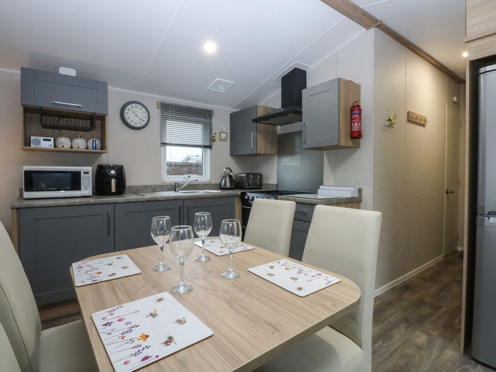 A kitchen with a table and chairs at Woodland Way in Benllech