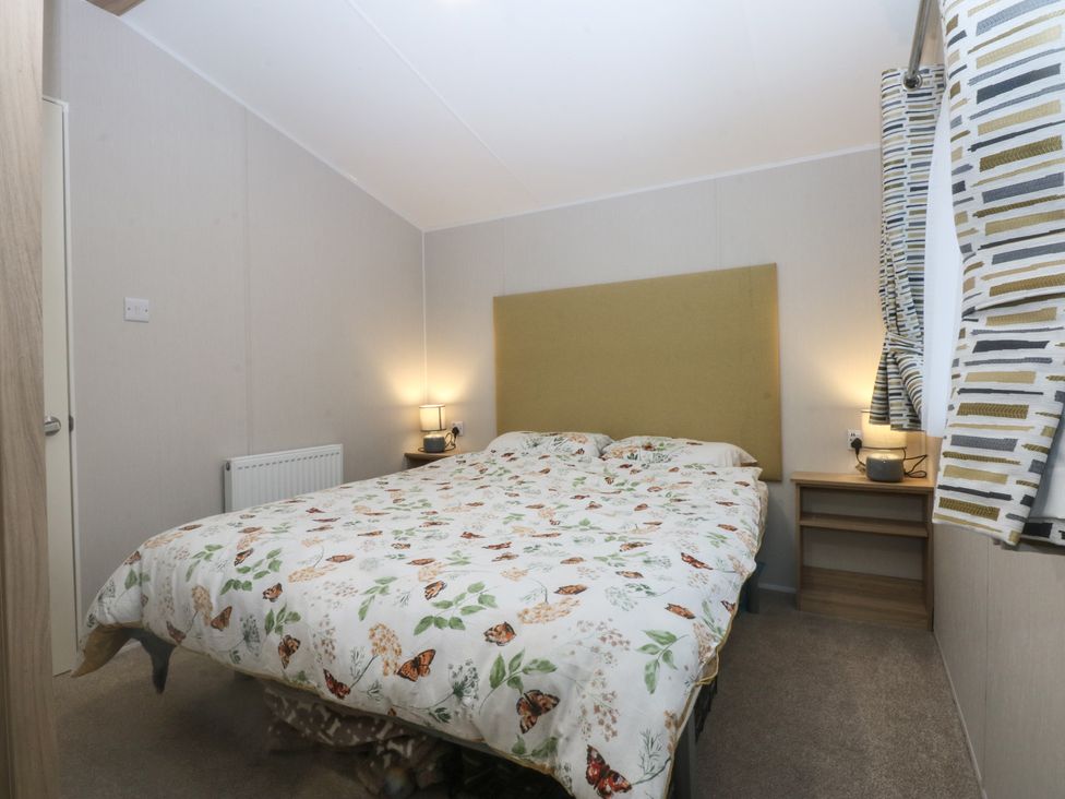 A bedroom with a bed and nightstand at Woodland Way in Benllech