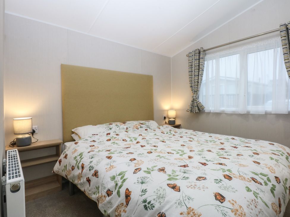 A bedroom with a bed and bedside tables at Woodland Way in Benllech