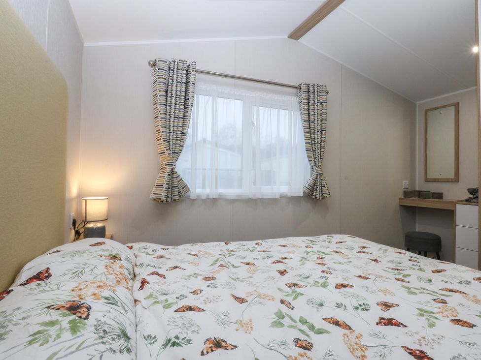 A bedroom with a bed and a window at Woodland Way in Benllech