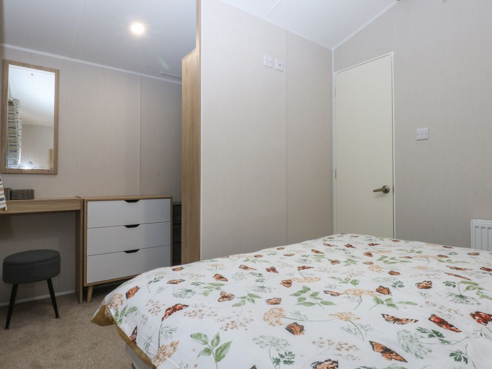 A bedroom with a bed and a dresser at Woodland Way in Benllech