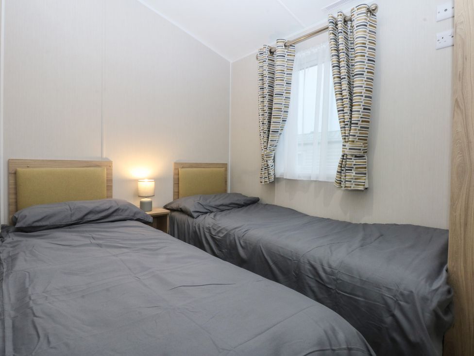 A bedroom with two single beds and a lamp at Woodland Way in Benllech