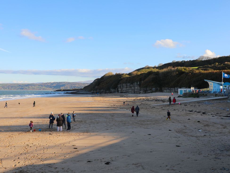 A beach with people walking and a cafe at Woodland Way in Benllech