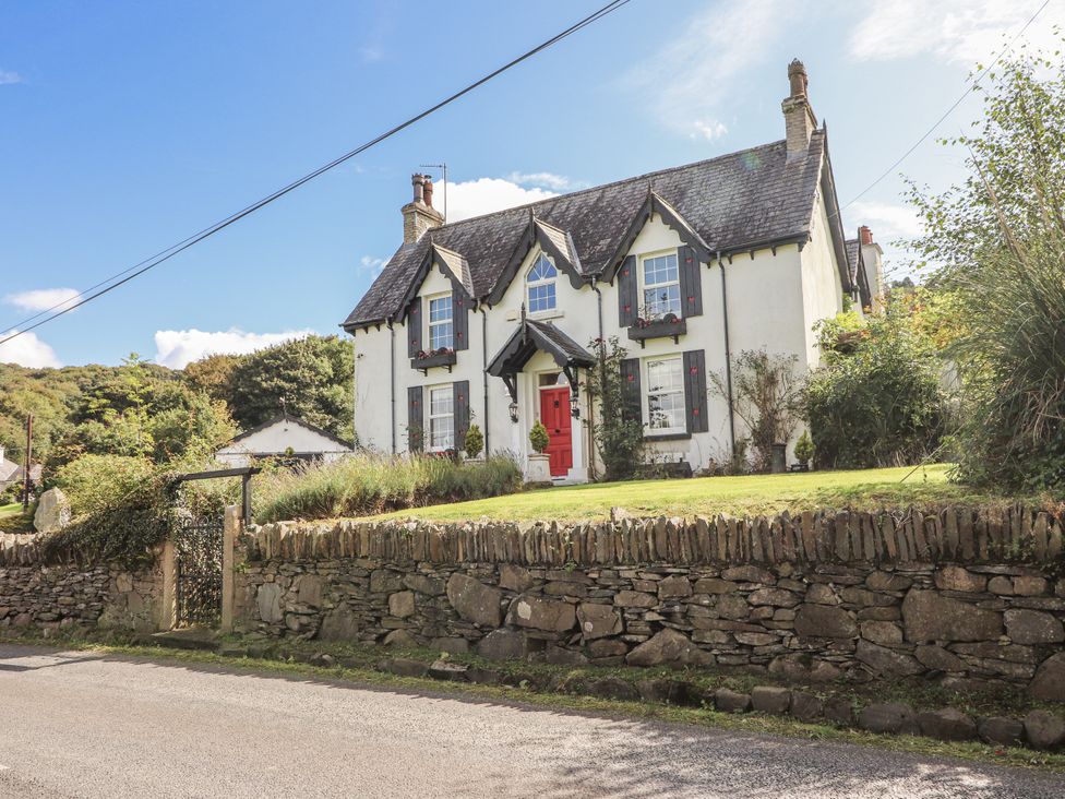 A house with a red door and a stone wall at White Heather Cottage in Killalou