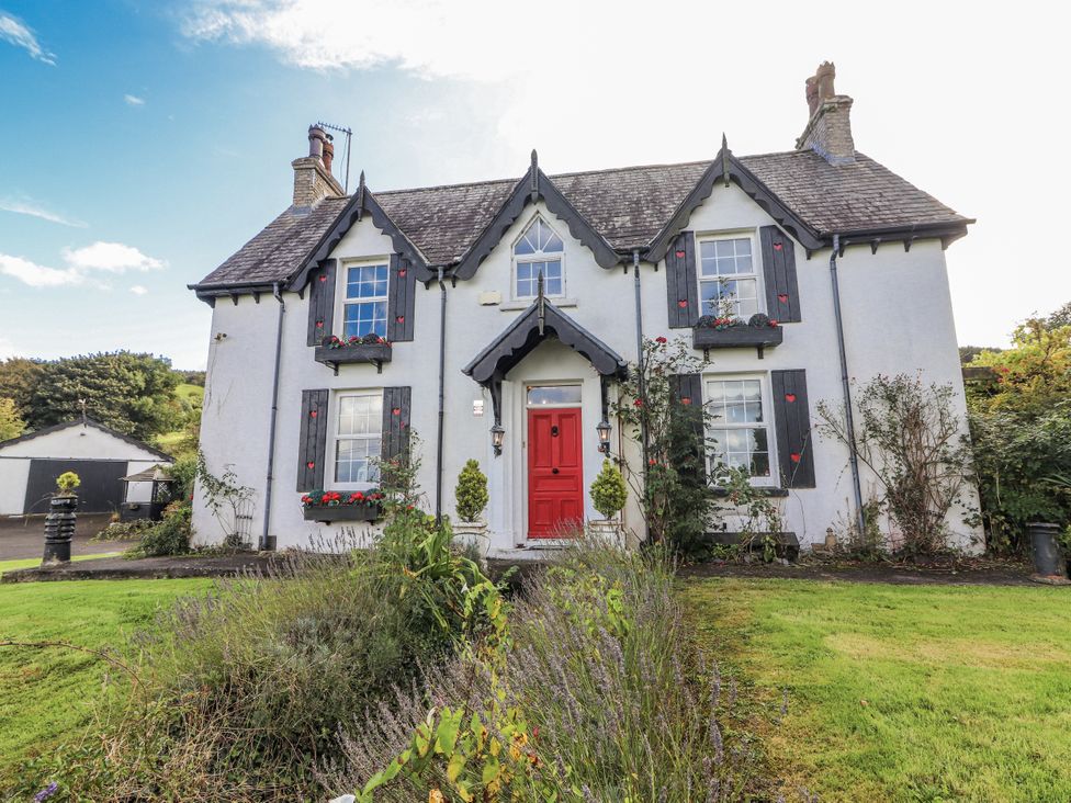 A house with a red door and flowers at White Heather Cottage in Killalou