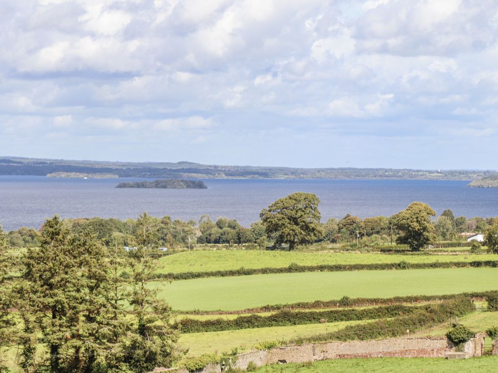 A scenic view of a lake and island surrounded by fields and trees at White Heather Cottage Killalou